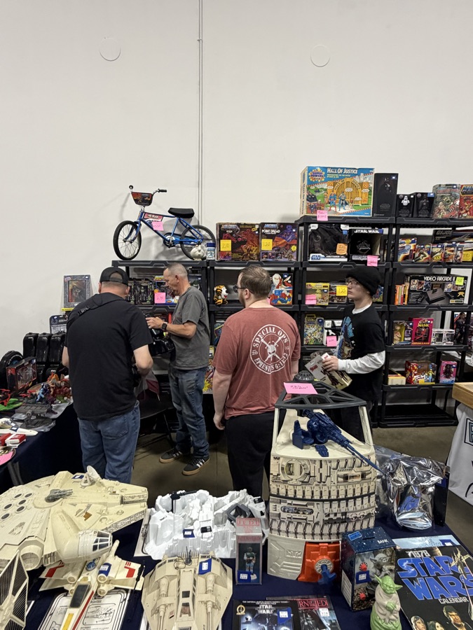 Vintage Star Wars ships, playsets, and boxed toys covering a vendor table